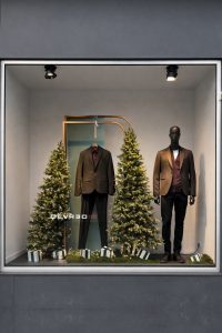 Vitrine de Noël 2024 Devred avec mannequins habillés, sapins illuminés, décor festif minimaliste et élégant