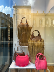 Vitrine Le Tanneur mettant en scène des sacs en cuir colorés associés à des volumes en fibres végétales, dans une composition élégante et naturelle